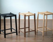Three bar stools with different seat materials on a wooden floor.